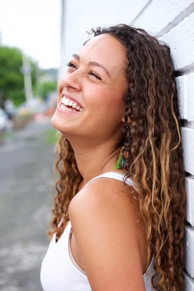 Joyeux jeune femme appuyé contre un mur — Photo