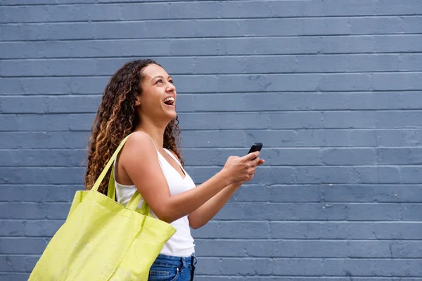 Mujer joven sonriente caminando con un teléfono móvil —  Fotos de Stock