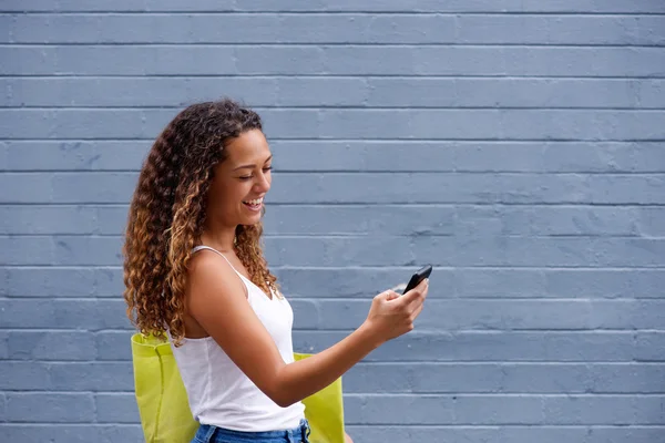 Mladá žena, chůzi a při pohledu na mobilní telefon — Stock fotografie