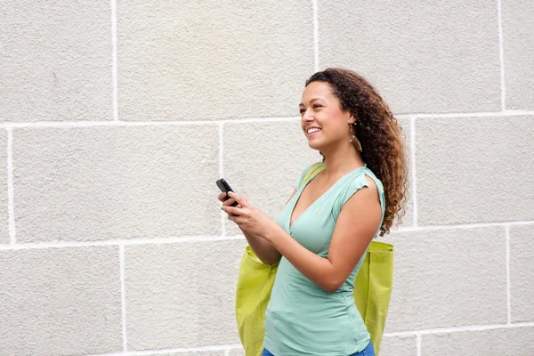 Mujer joven sonriendo al aire libre con teléfono móvil — Foto de Stock