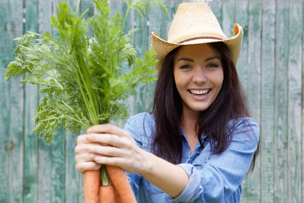 Mujer sonriente sosteniendo racimo de zanahorias —  Fotos de Stock