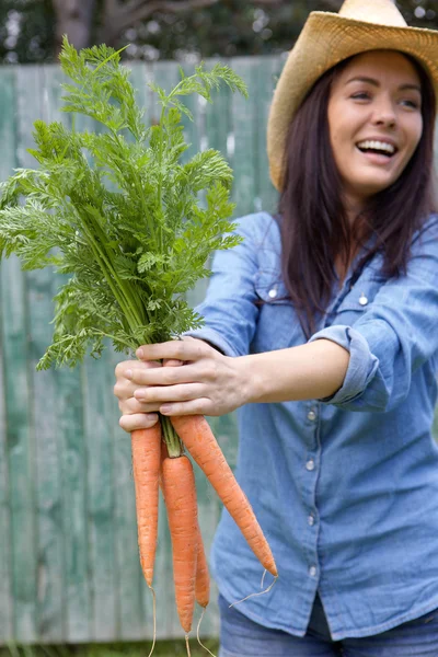 Aantrekkelijke jonge vrouw die lacht met bos van wortelen — Stockfoto