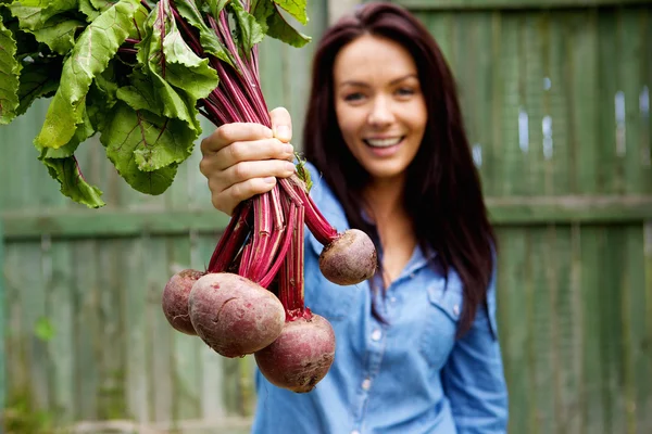 Lächelnde Frau zeigt ein Bündel Rote Beete — Stockfoto