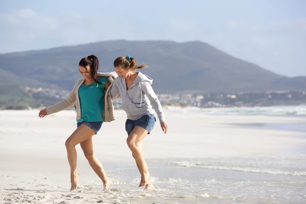 Vrienden van de twee vrouwen lopen samen op het strand — Stockfoto