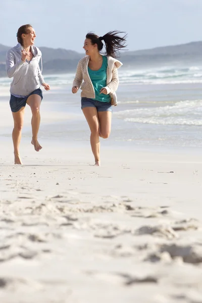 两个女人笑和运行在沙滩上 — 图库照片