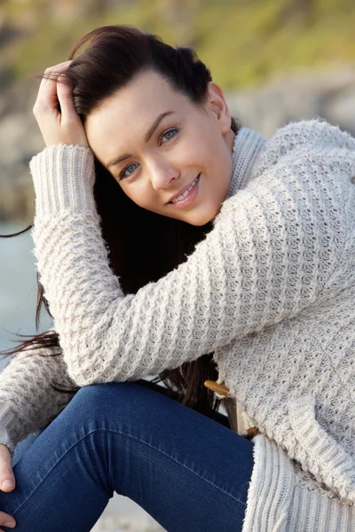 Smiling woman sitting outside in warm sweater — Stock Photo, Image