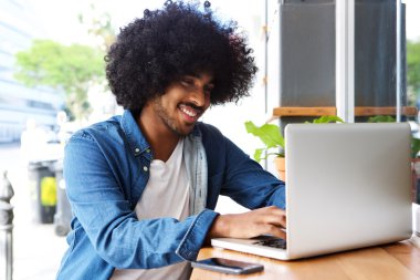 Kafede dizüstü bilgisayar üzerinde çalışan genç modern adam