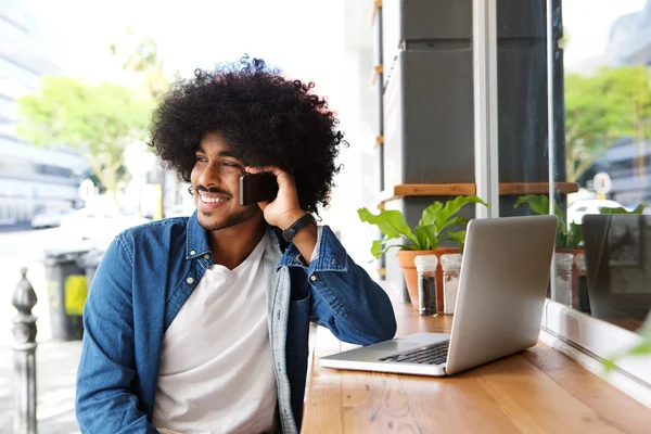 Koele kerel met behulp van mobiele telefoon en laptop — Stockfoto