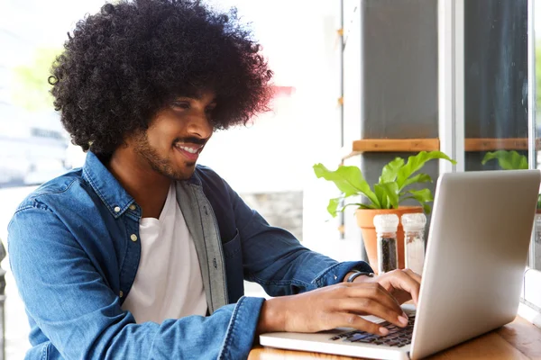 Homme souriant avec afro travaillant sur ordinateur portable — Photo