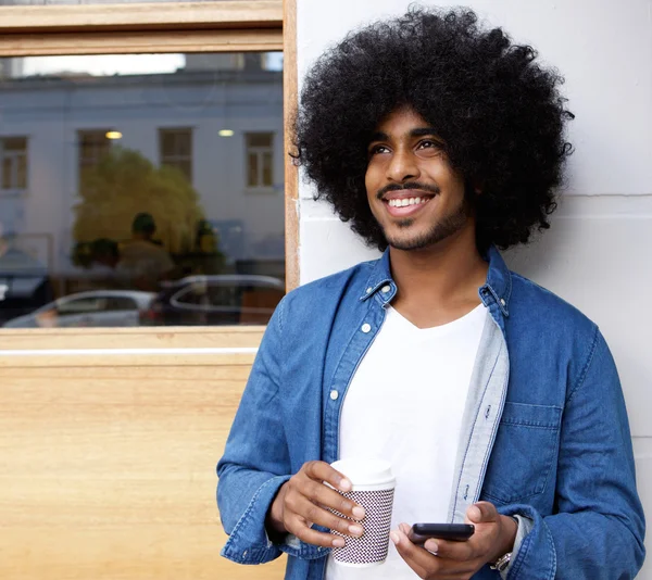 Człowiek z afro stojących na zewnątrz z telefonu komórkowego reklamy kawy — Zdjęcie stockowe