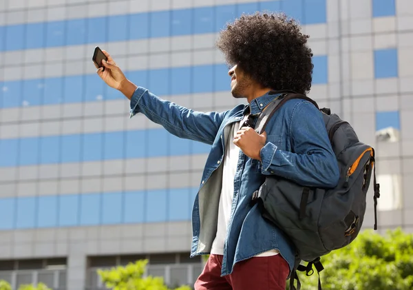 Joven hombre negro con bolsa tomando selfie —  Fotos de Stock