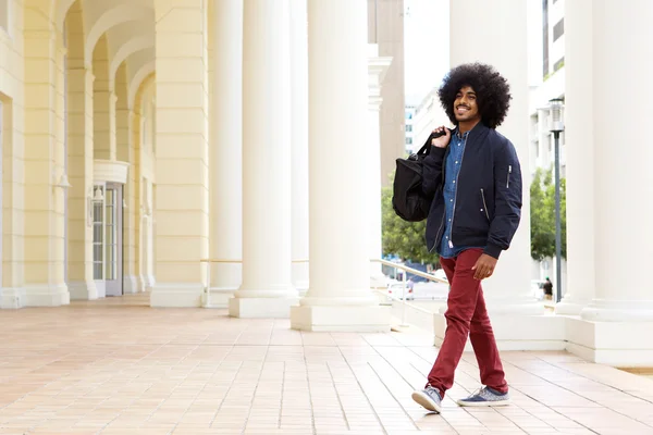 Sorridente ragazzo di moda che cammina fuori con borsa da viaggio — Foto Stock