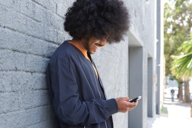 Cep telefonu kullanarak afro ile gülümseyen genç adam