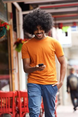 Gülümseyen adam şehirde cep telefonu ile yürüme