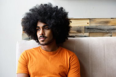 Genç adam, ev düşünme oturan afro ile siyah