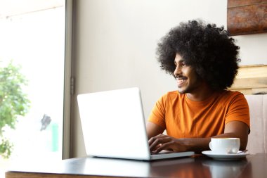 Laptop ile masada oturan mutlu öğrenci