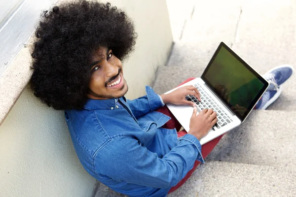 Tersenyum pemuda kulit hitam menggunakan laptop — Stok Foto
