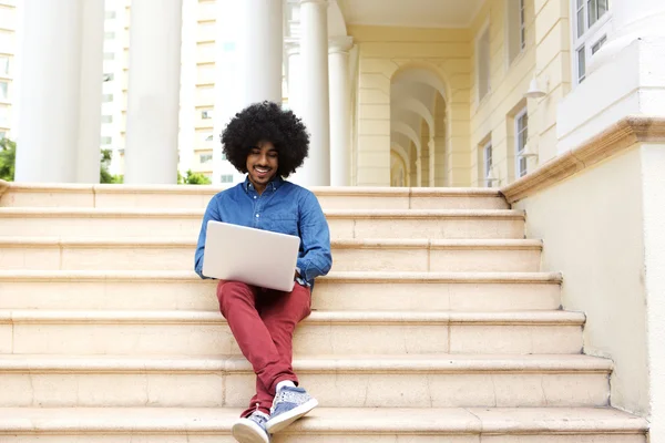 Afro homme assis sur les marches en utilisant un ordinateur portable — Photo