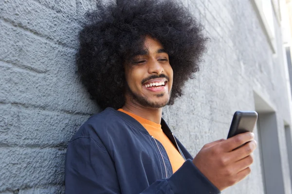 Uśmiechnięty mężczyzna afro przy użyciu telefonu komórkowego — Zdjęcie stockowe