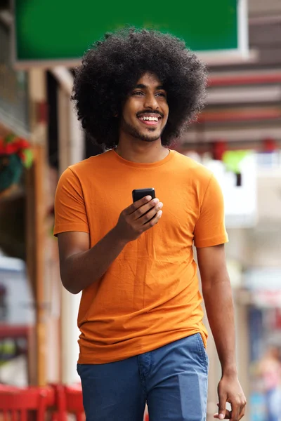 Homme noir souriant marchant avec téléphone portable — Photo