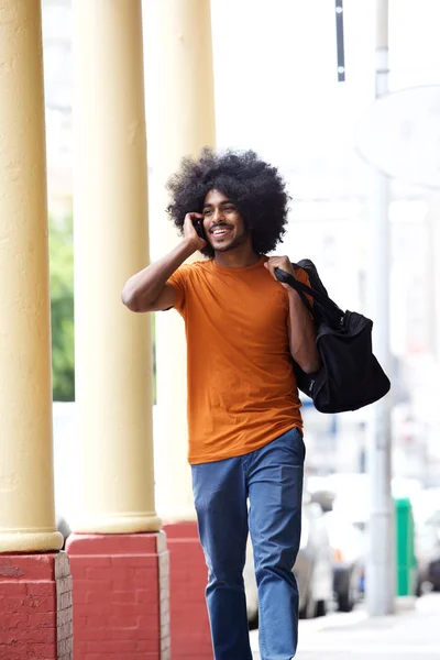 Cool guy talking on cell phone carrying bag in town — Stock Photo, Image