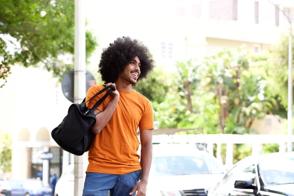 Smiling black guy carrying travel bag — Stock Photo, Image