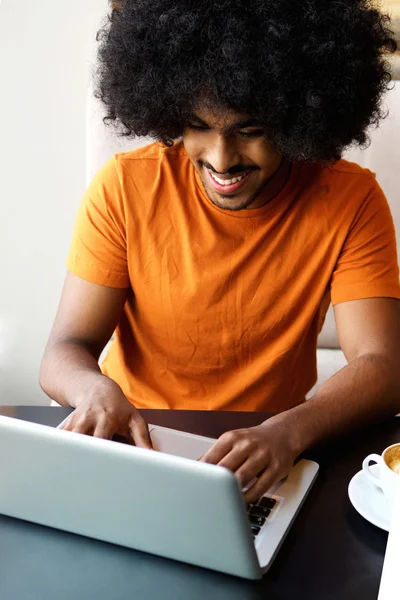 Sorridente giovane uomo africano americano utilizzando il computer portatile a casa — Foto Stock