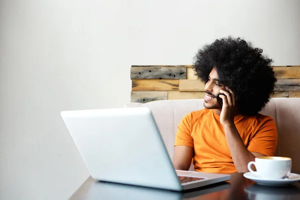 Fiatal férfi ült a laptop és mozgatható telefon — Stock Fotó