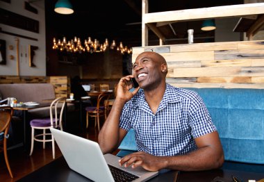 Gülümseyen adam cep telefonuyla konuşuyor.