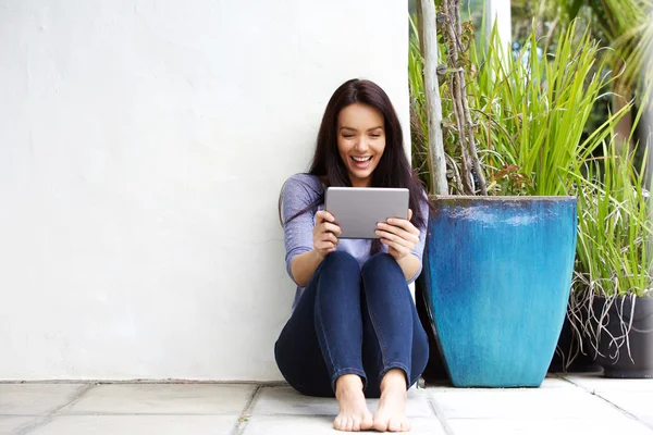 Glückliche junge Frau schaut auf Tablet — Stockfoto