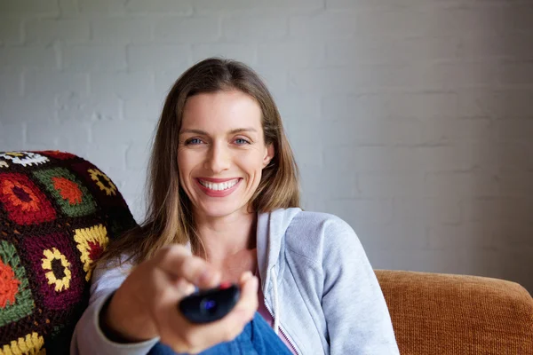 Woman smiling with TV remote control — Stock Photo, Image