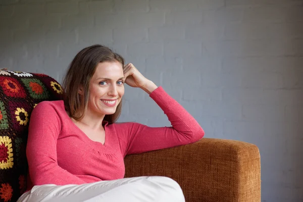 Lächelnde Frau entspannt sich auf Sofa — Stockfoto