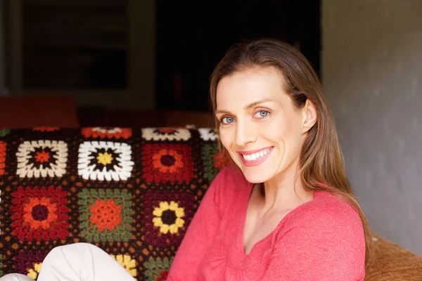 Mujer sonriente sentada en casa — Foto de Stock