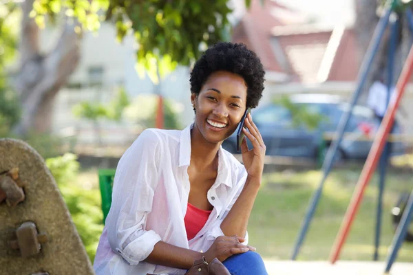 Aantrekkelijke jonge vrouw in een park en praten op mobiele telefoon — Stockfoto