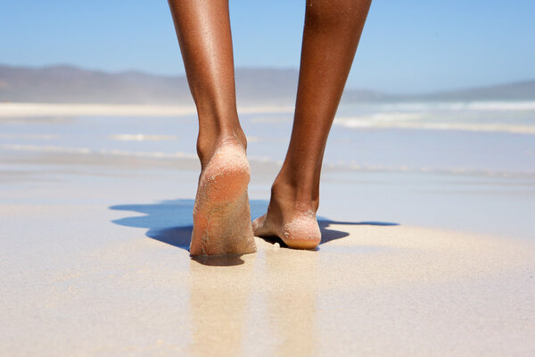 Женщина ходит босиком по пляжу
