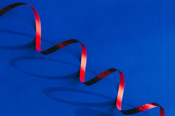 Mavi arkaplanda dalgalı kırmızı kurdele Yeni Yıl Dekoru.