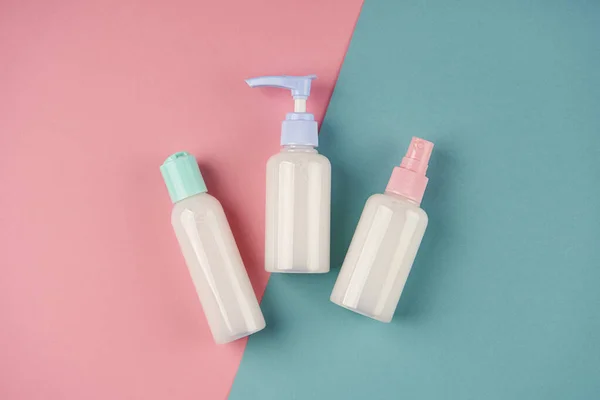 Mavi ve pembe arka planda sabun ve krema şişeleri. Krem, losyon, jöle, yüz köpüğü veya cilt bakımı. Kozmetik güzellik ürünü markalaşma modeli. Boşluğu kopyala