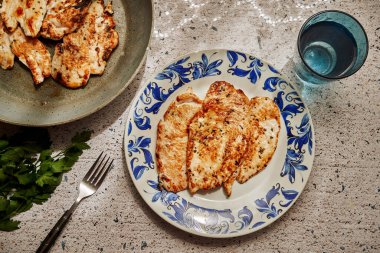 Taze terbiye edilmiş göğüs filetosu ve güneş ışığı altında bir tabak.