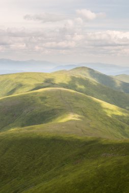 Yeşil dağlar ve mavi bulutlu gökyüzü