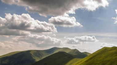 Yeşil dağlar ve mavi bulutlu gökyüzü