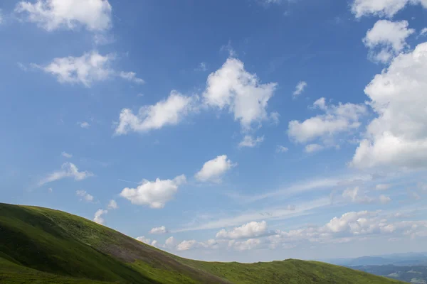 Montagnes vertes et ciel nuageux bleu — Photo