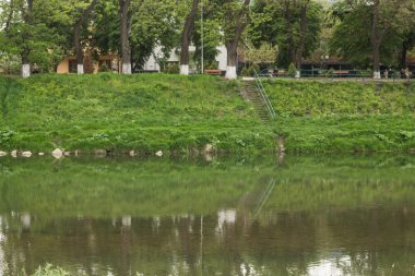 Nehir akışı kasaba ve bankalar üzerinde yeşil çimen