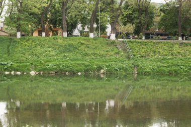 Nehir akışı kasaba ve bankalar üzerinde yeşil çimen