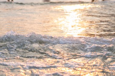 Deniz suyu yakınındaki kıyı şeridi arka plan günbatımı ışıkta dalgalar.