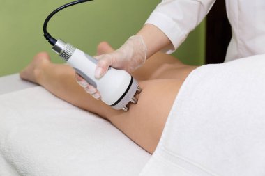 Spa güzellik uzmanı RF kaldırma manifestosunu elinde tutuyor ve uyluktaki sorunlu bölgeler için prosedürü uyguluyor..