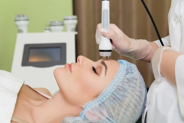 A young woman is lying on the RF-lifting procedure for face skin tightening and face contour correction. Close-up.