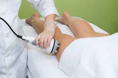 Donanım kozmetolojisi kullanılarak bacak şekillendirme prosedürü. Vücudunu şekillendirmek için genç bir kadının kalçalarını kaldıran modern radyofrekans..