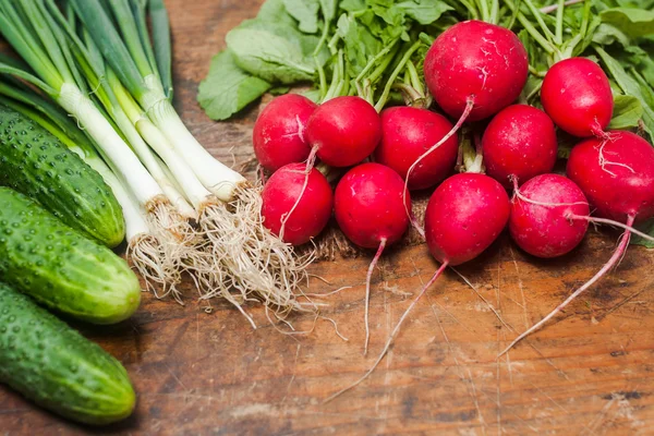 Verse radijs, ui en komkommers op oude rustieke houten tafel — Stockfoto