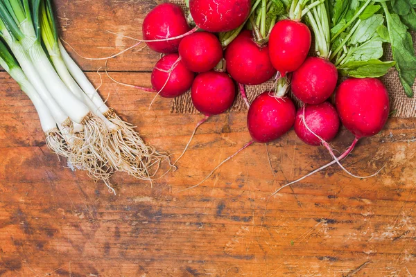 Fresh radishes, onion and cucumbers on old rustic wooden table Stock Image