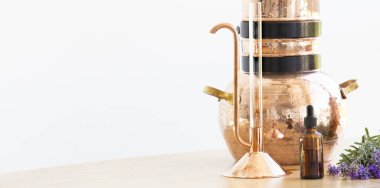 Ahşap masada yağlı çiçeklerle damıtma aleti..